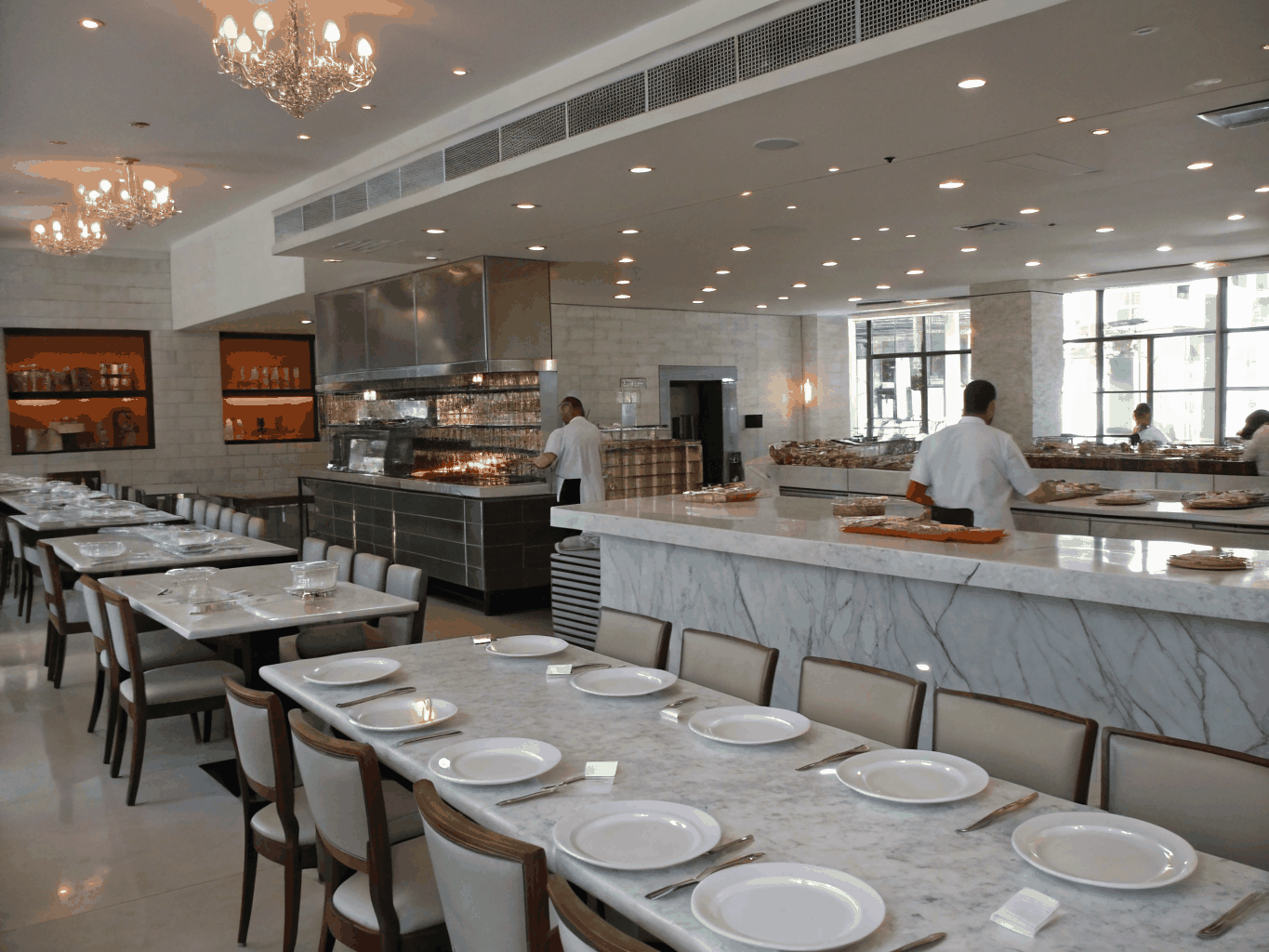 Modern restaurant dining hall with open kitchen and warm ambient lighting